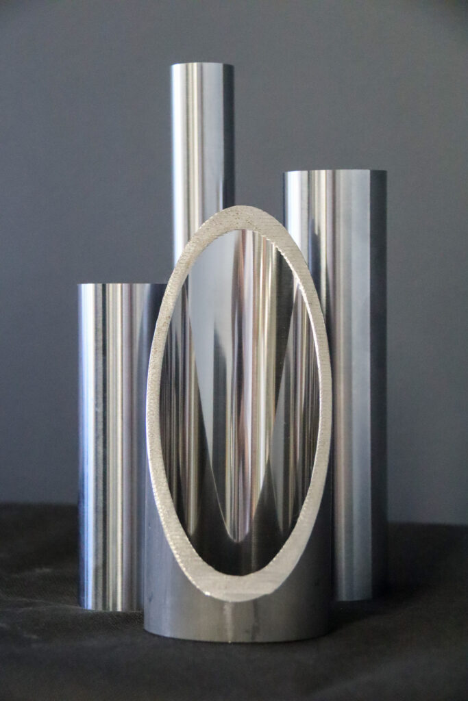Close up of cut hydraulic cylinder tube and chrome bars on table