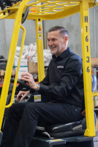 Jason Lane, Managing Director of VH Steels, operating a forklift while working in warehouse